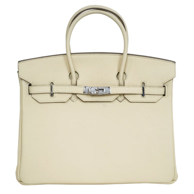 Beige handbag with silver hardware on a light gray background