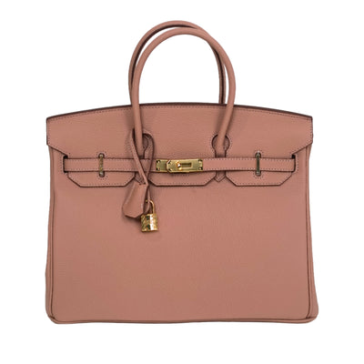 Pink handbag with gold hardware on a white background